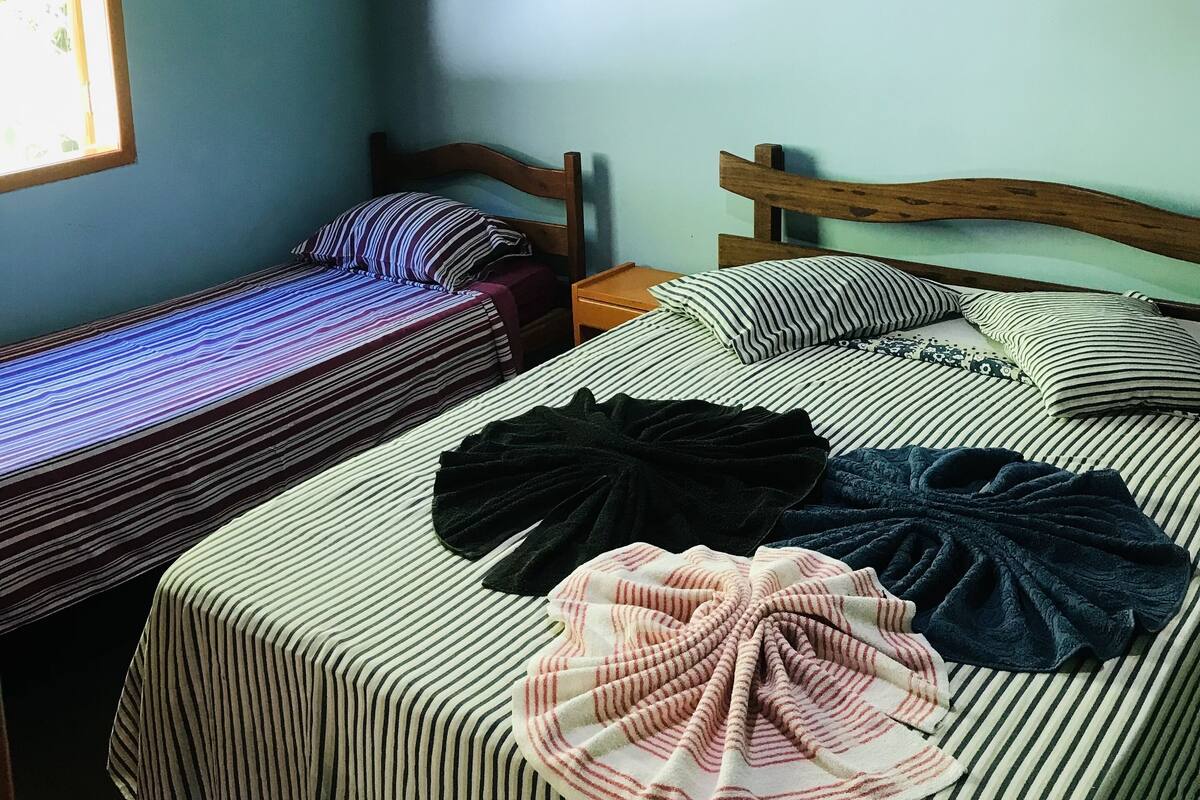 Una habitación con dos camas, una lámpara colgante y un ventanal.