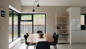 Een moderne keuken met een groot raam, een eettafel met stoelen en een ingebouwde boekenkast.