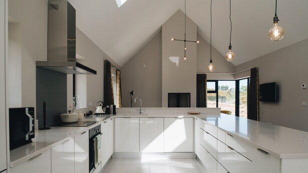 Een moderne keuken met een groot eiland, een ingebouwde oven en een dakraam.