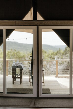 A sliding glass door leading to an outdoor deck with a view of a mountainous landscape.