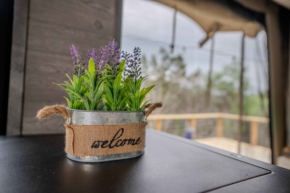 A metal pot with a burlap band and the word "welcome" on a balcony table.