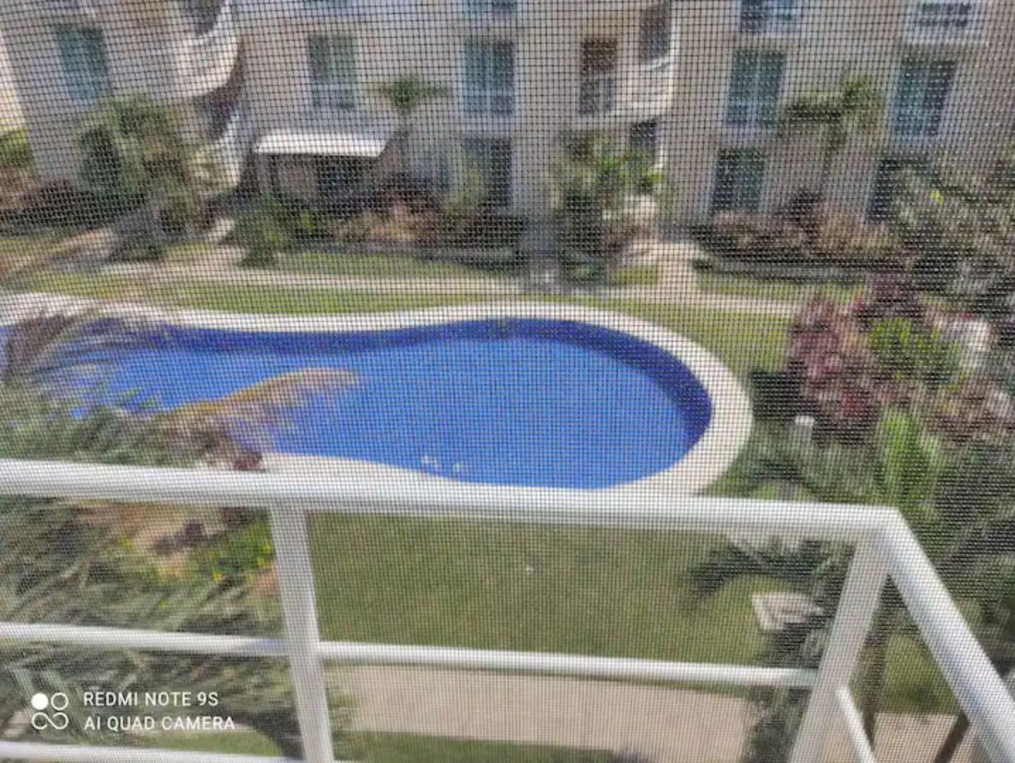 Blick auf einen Swimmingpool, umgeben von einer Rasenfläche und einem Gebäude mit Balkon.