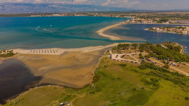 An aerial view of a coastal area with a beach, parking lot, and buildings. - Villa NiA Zadarvillas (Nin)