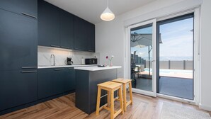 A modern kitchen with dark cabinets, a wooden countertop, and two wooden stools. - Villa NiA Zadarvillas (Nin)