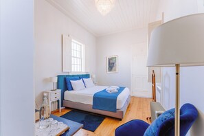 Un dormitorio con cama, mesita de noche, lámpara y una silla.