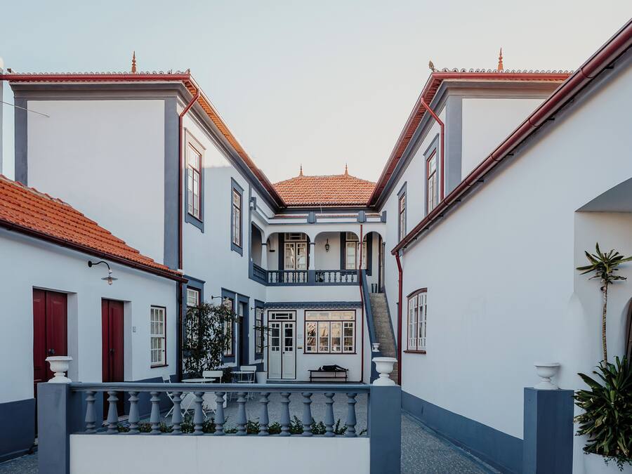 Uma rua estreita com edifícios em ambos os lados, uma escadaria central e um pequeno jardim.