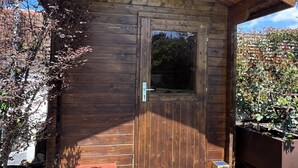 A wooden cabin with a door, a small bench, and a wooden deck. - Galricho Heritage House (Murtosa)