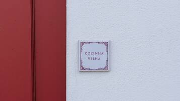 Una puerta roja y una pared blanca con un letrero que dice 'COZINHA VELHA'.
