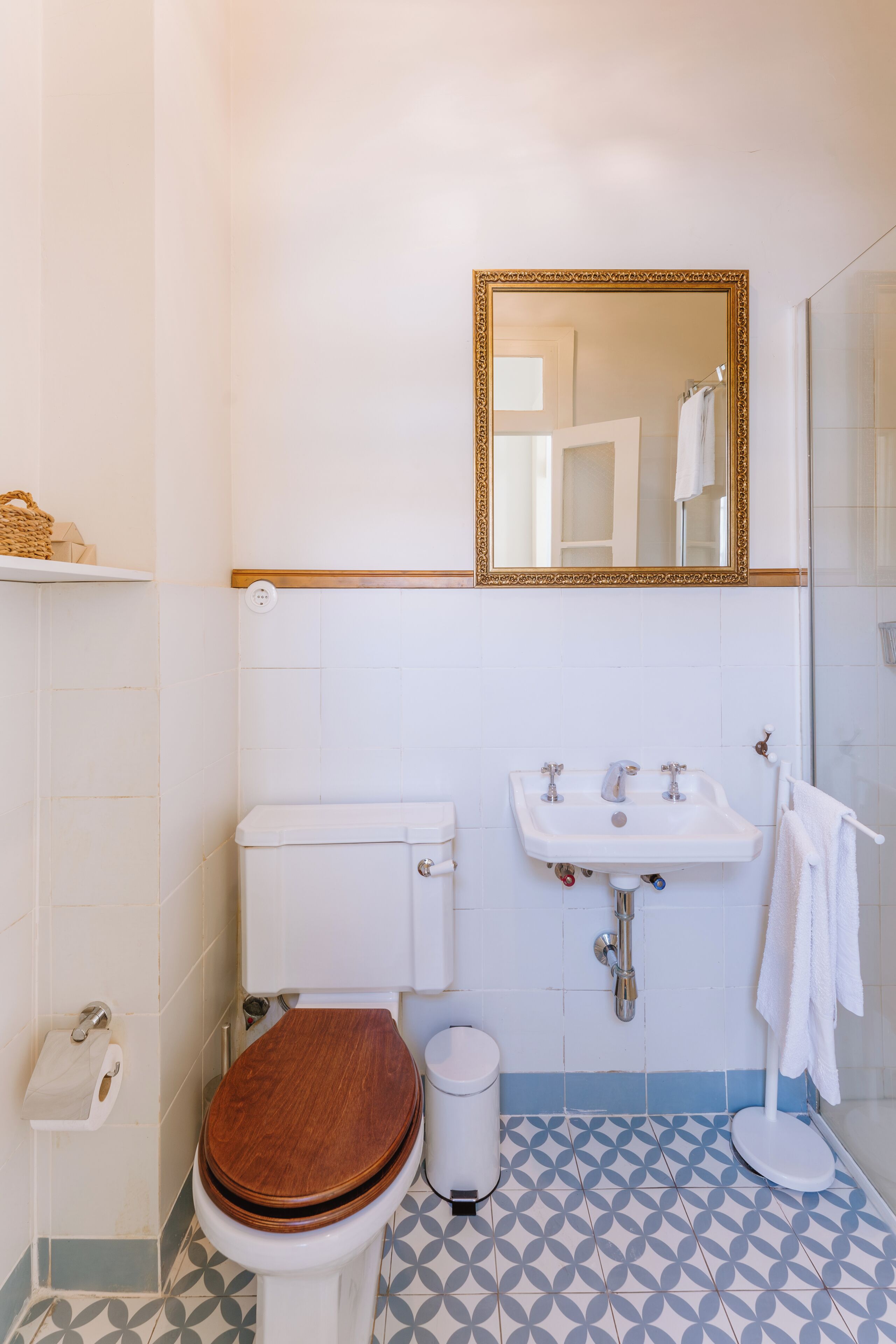 A bathroom with a toilet, sink, and mirror.