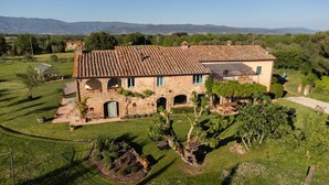 Una villa de piedra con tejado de baldosas, ventanas arqueadas y un jardín bien cuidado.