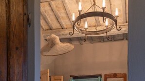 Un dormitorio con piso de madera, una cama con manta color beige, un candelabro y vistas al verdor exterior.