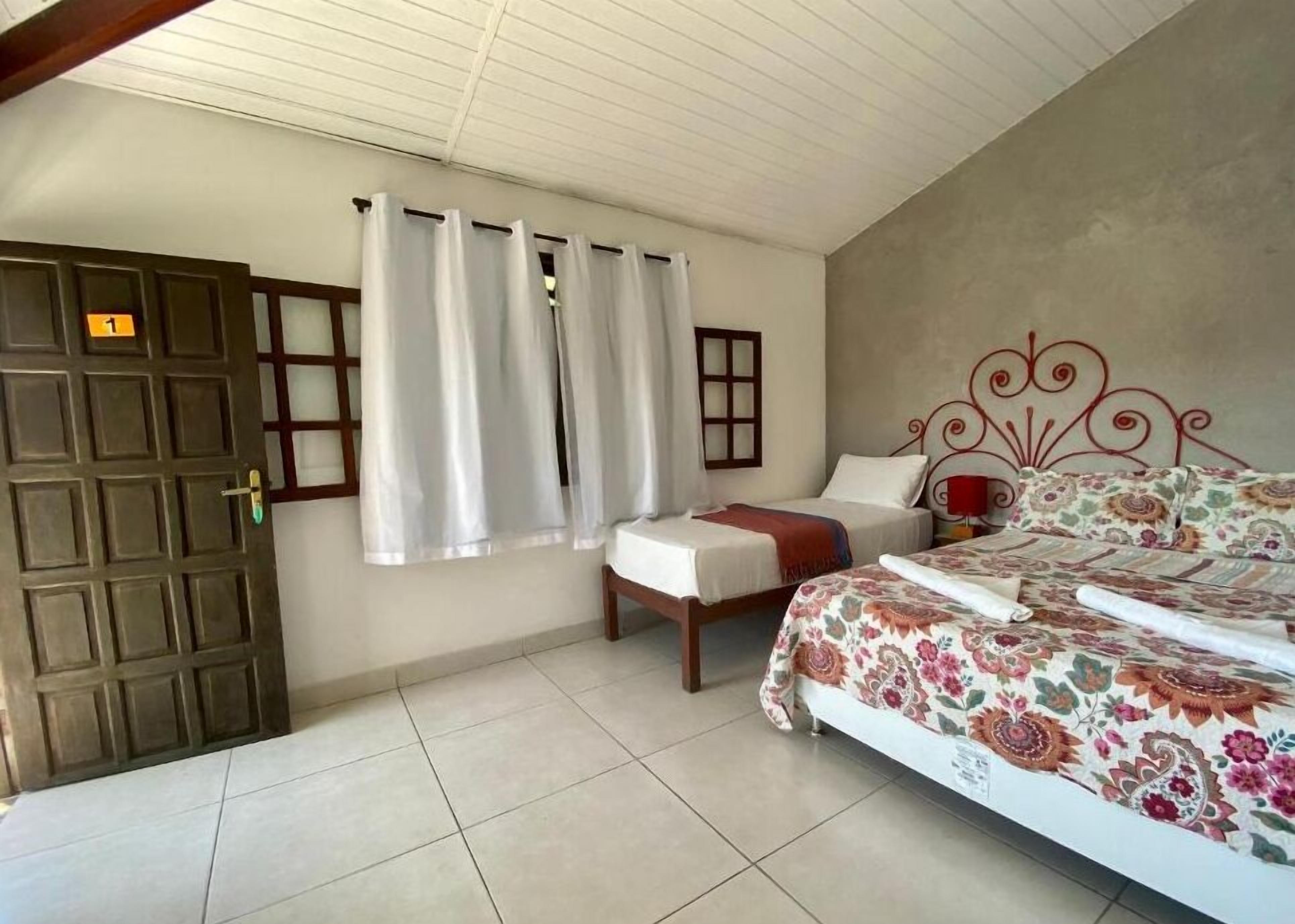 A bedroom with a bed, a chair, a small table, and a door.