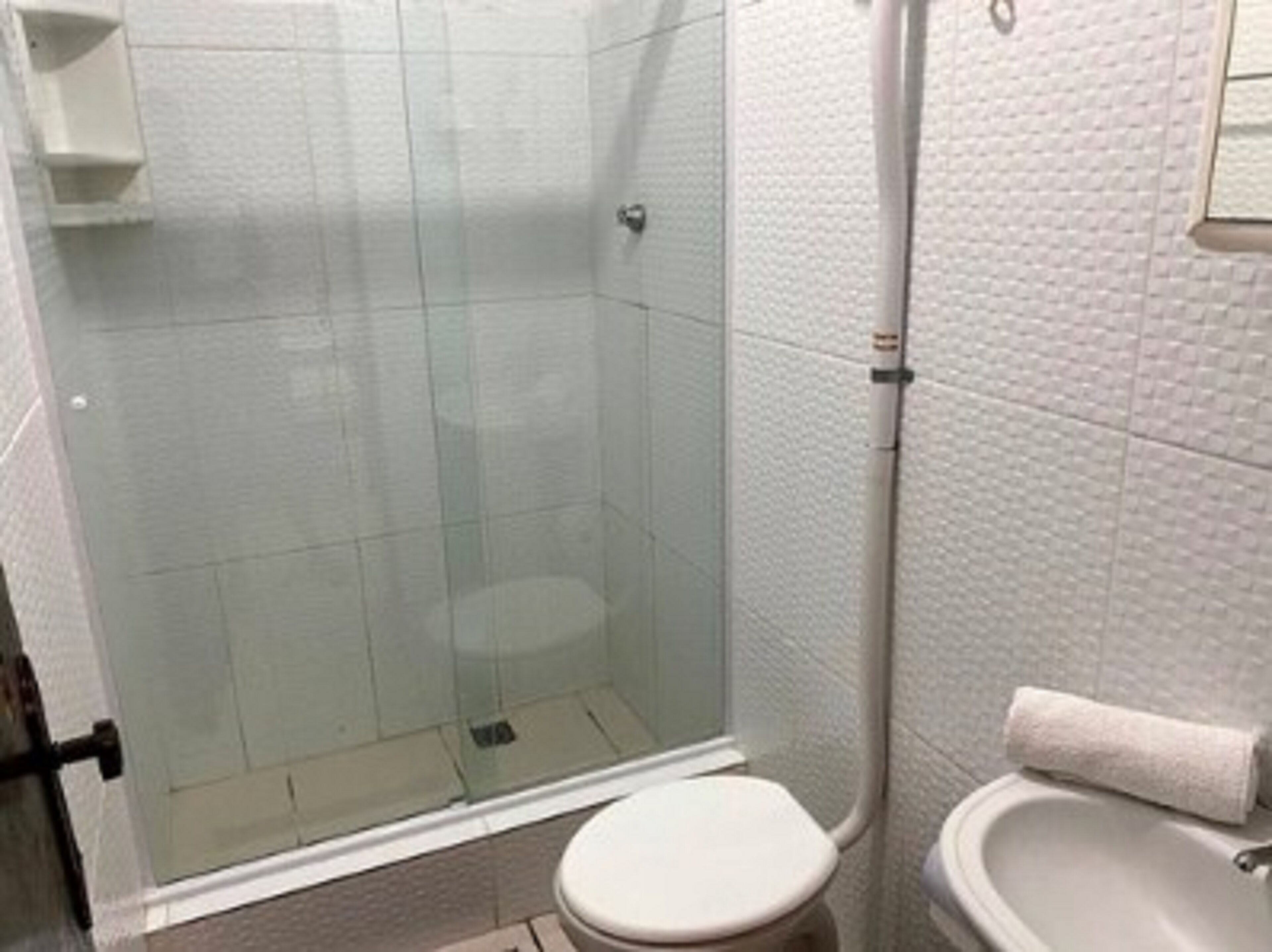 A bathroom with a glass shower enclosure, a toilet, and a sink.