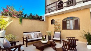 A spacious patio with outdoor furniture, a large planter, and a balcony with a view. - Pousada Porto Búzios (Búzios)