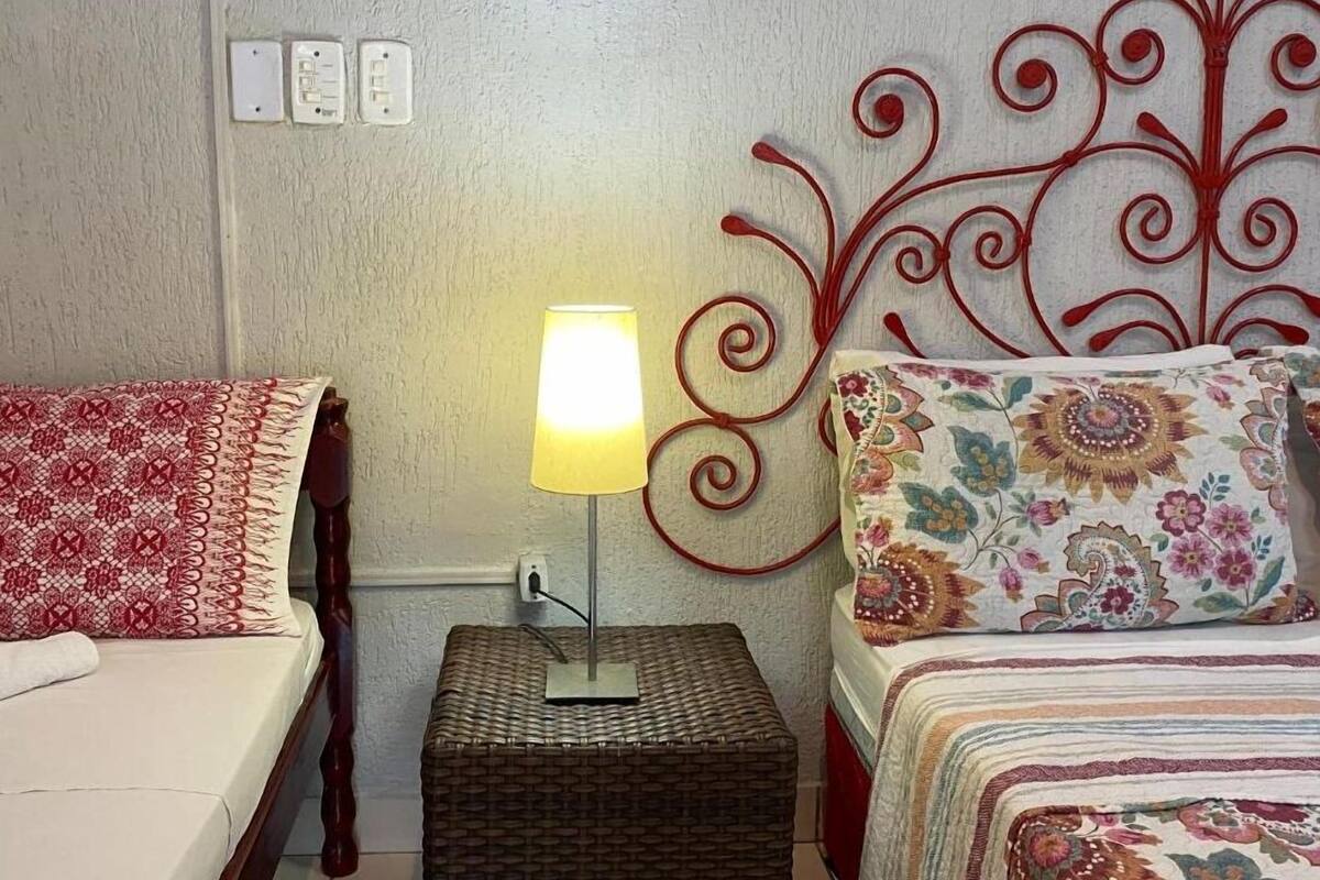 A bedroom with a bed on the left, a bedside lamp, and a decorative metal headboard on the right.