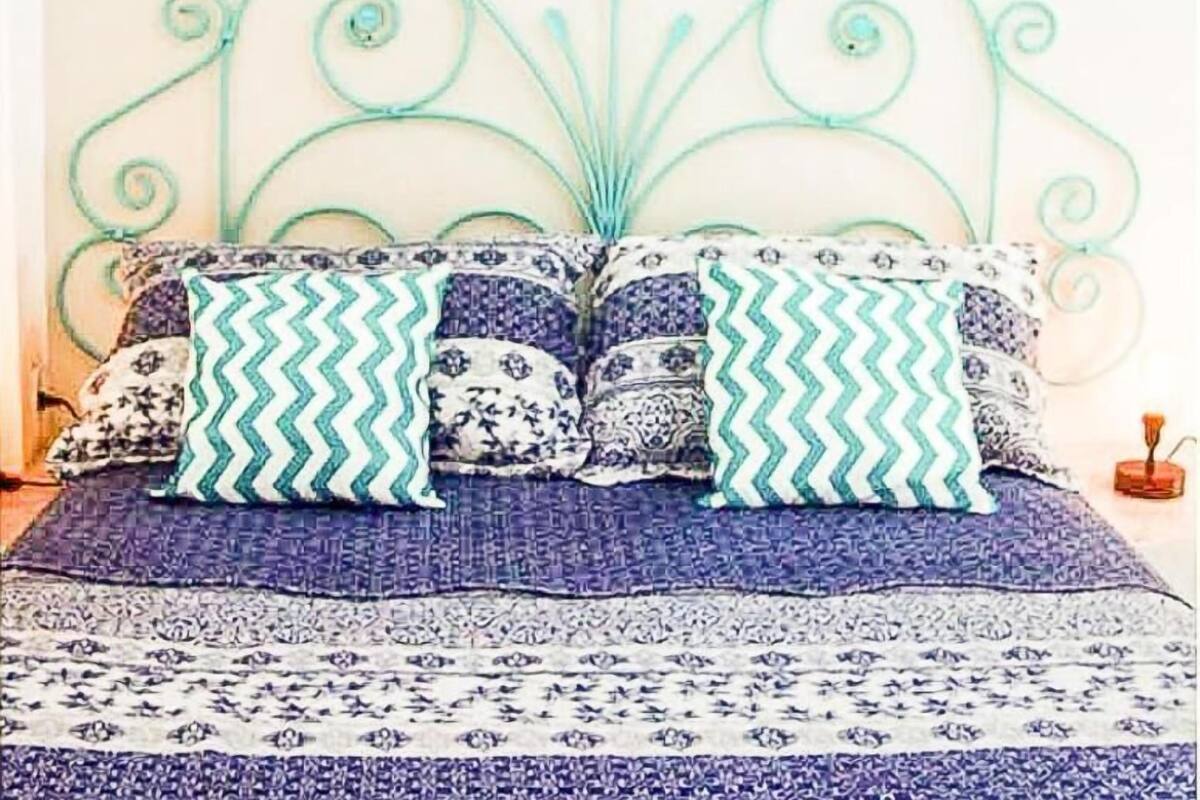 A bed with a metal headboard, patterned bedding, and decorative pillows.