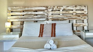 A neatly made bed with a wooden headboard, white linens, and rolled towels. - Pousada Porto Búzios (Búzios)
