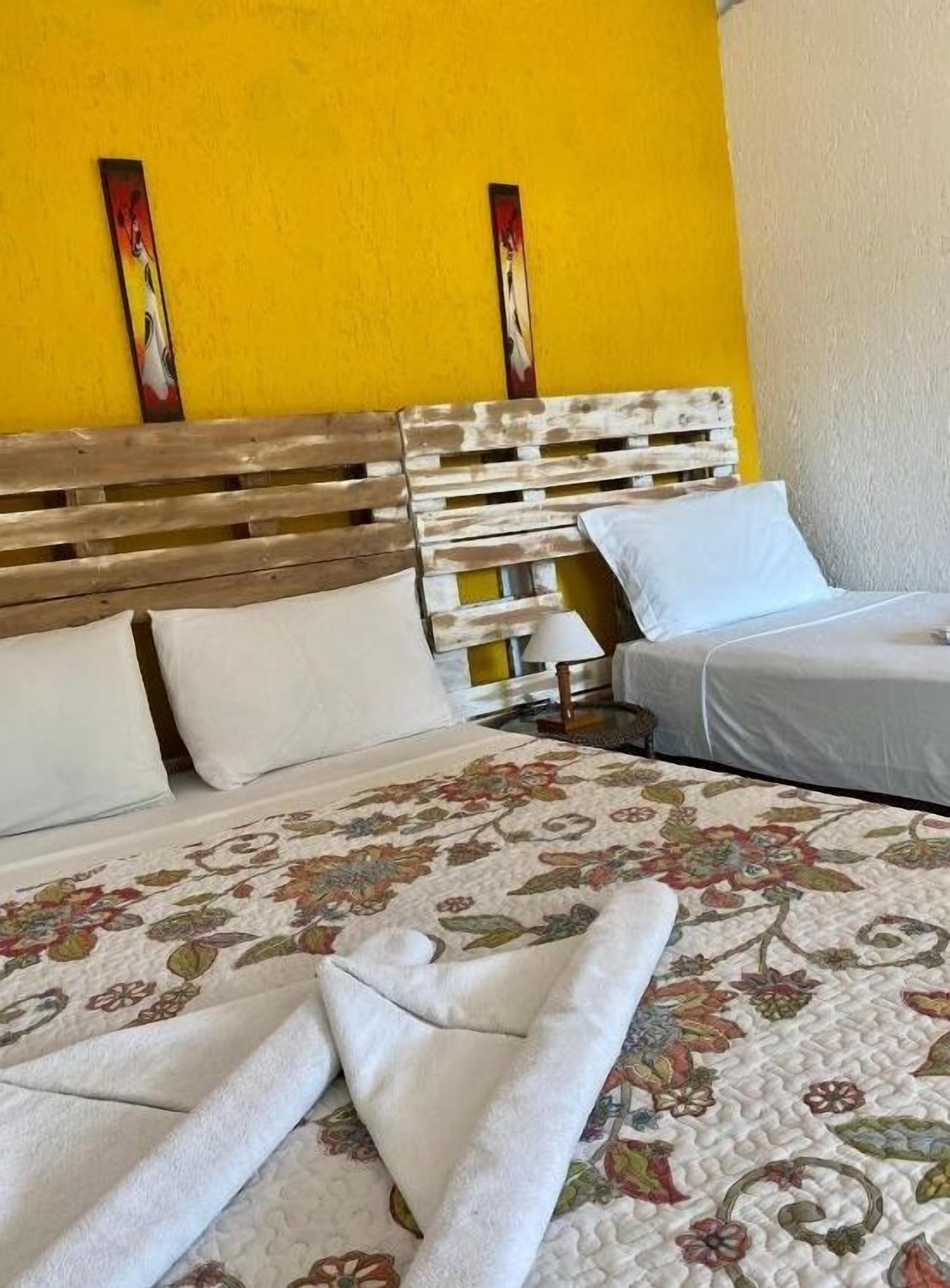 Una cama con colcha estampada, almohadas blancas y cabecera de madera.