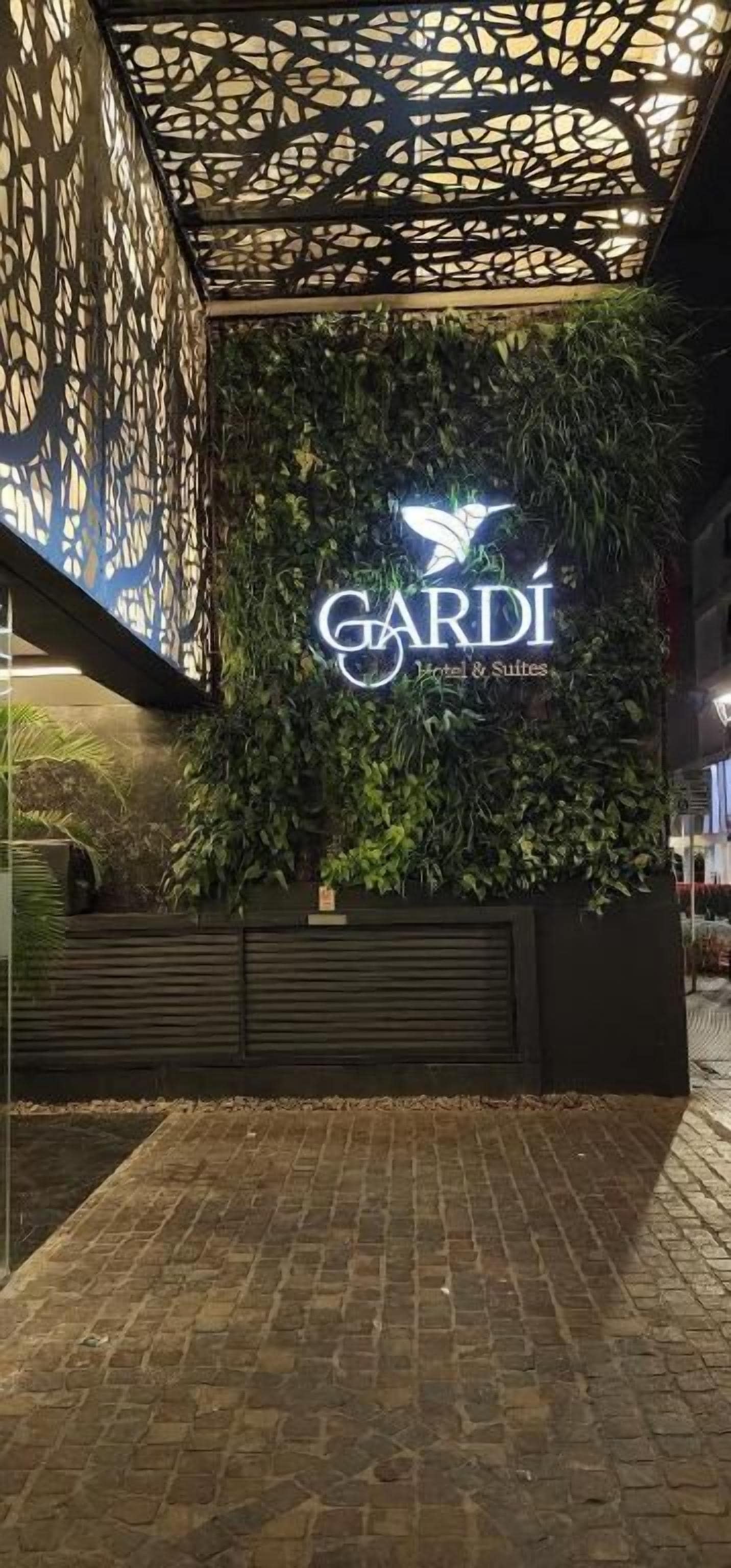 Entrada de un hotel con un cartel que dice 'GARDI Hotels & Suites' y un techo decorativo.