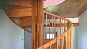 A wooden spiral staircase with a wooden railing and a ceiling with wooden beams. - Enjoy the Summertime Beaches, Concerts and Events in Prince Edward County! (Prince Edward)