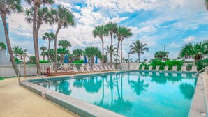 A swimming pool with lounge chairs and palm trees. - Ocean Front Two Bedroom Condo, Jensen Beach, FL  2869369 (Jensen Beach)