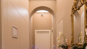 A hallway with a wooden floor, a white door at the end, and a mirror on the right. - Atelier Altafronte (Florence)