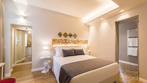 A modern hotel room with a large bed, a small bedside table, a red chair, and a decorative wall piece. - Atelier Altafronte (Florence)