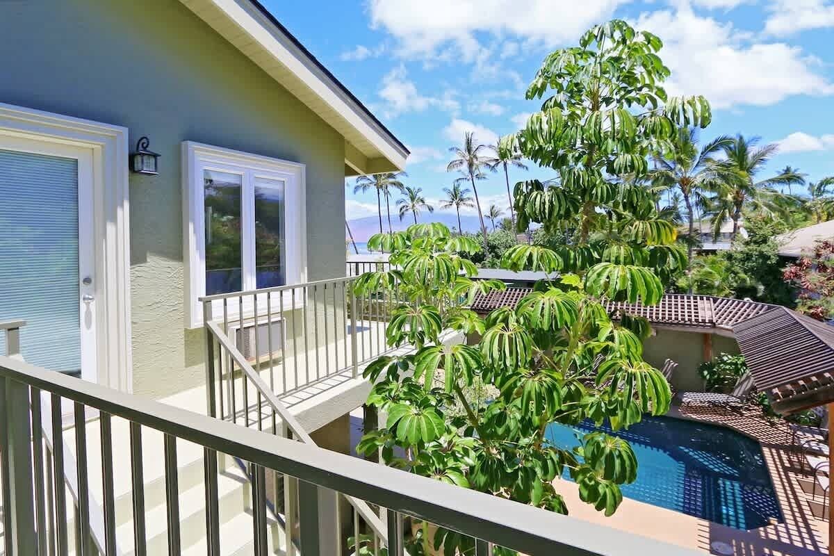 Propiedad residencial con balcón, piscina y vegetación tropical.