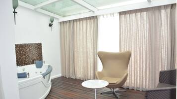 Relax in a serene space with a bathtub, side table, and comfortable seating area.