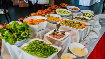 A buffet table with various dishes including salads, vegetables, and seafood.