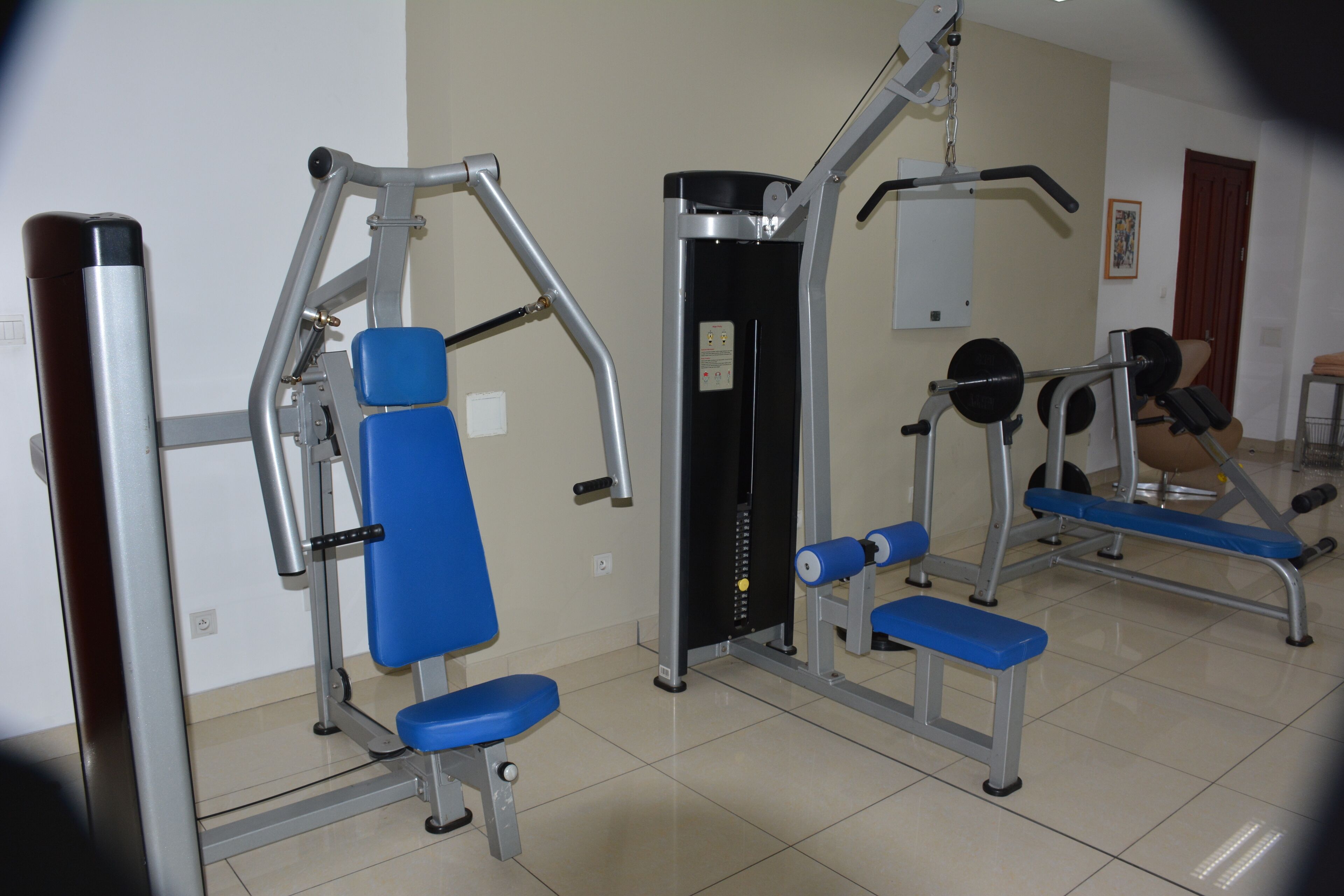 A gym with various exercise equipment including a bench press, a squat rack, and a cable machine.