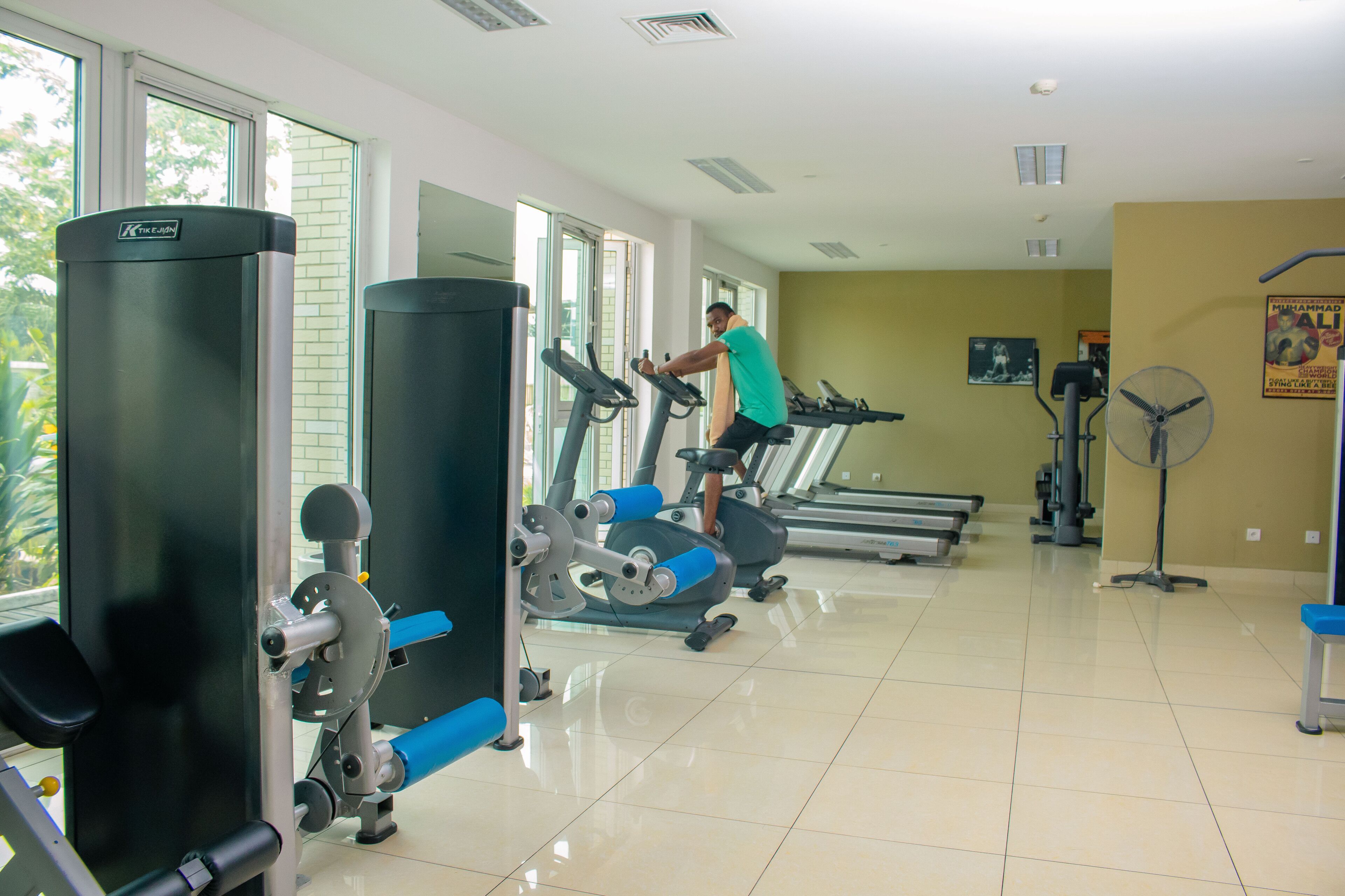 Un gimnasio con cintas de correr, máquinas de pesas y un ventilador.
