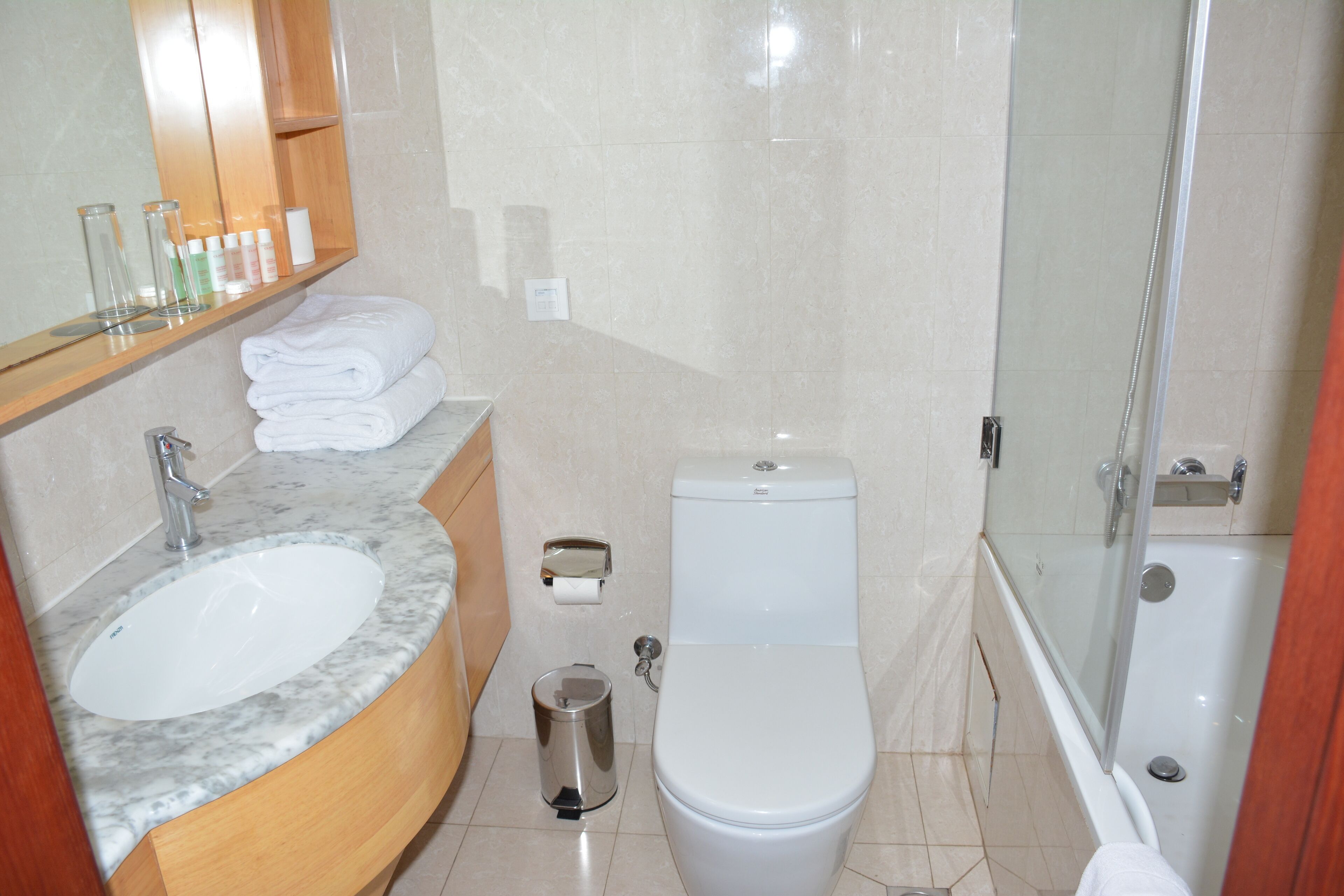 A bathroom with a marble sink, toilet, and glass-enclosed shower.