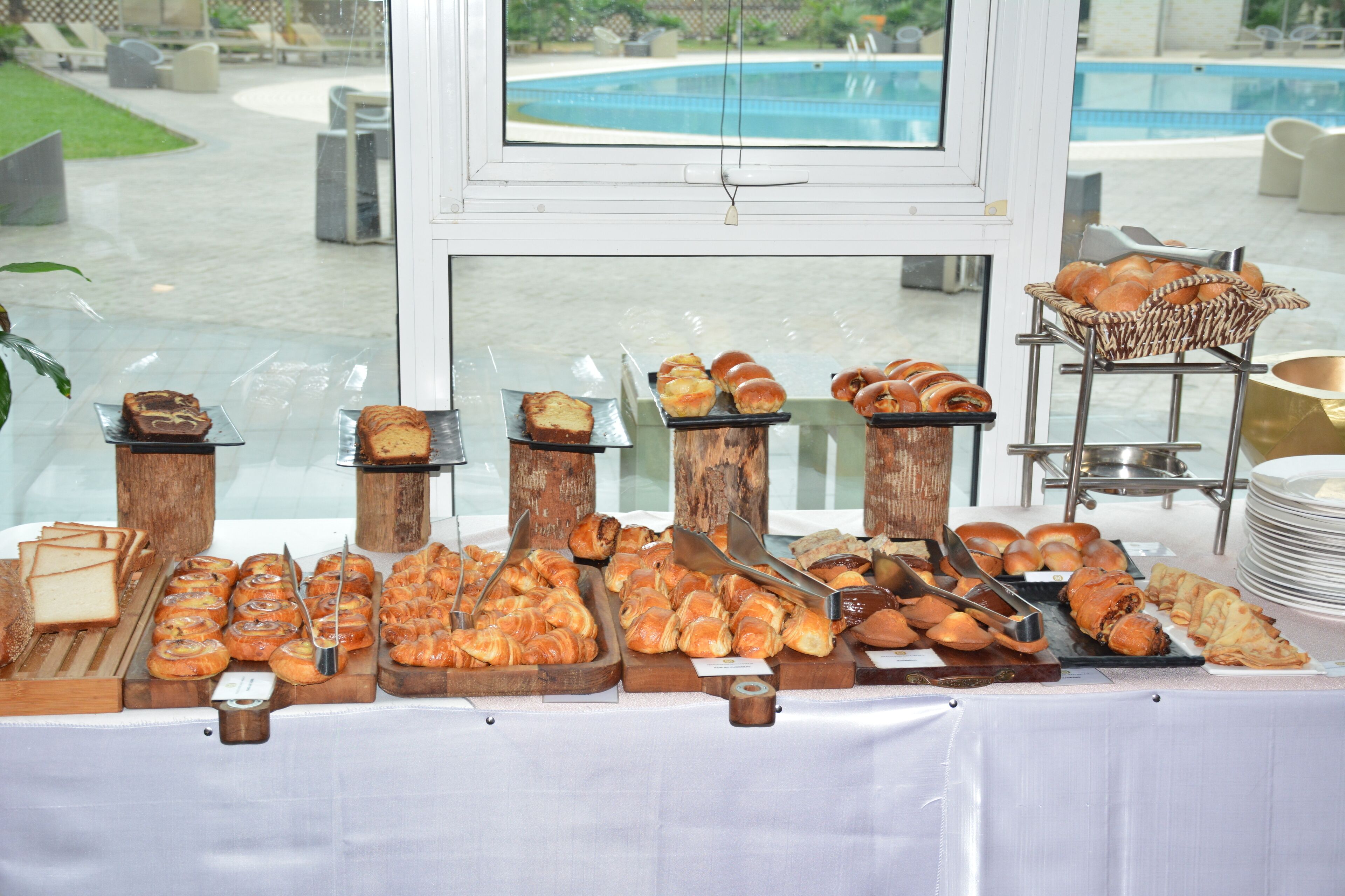 A buffet with various baked goods and pastries displayed on wooden stands.