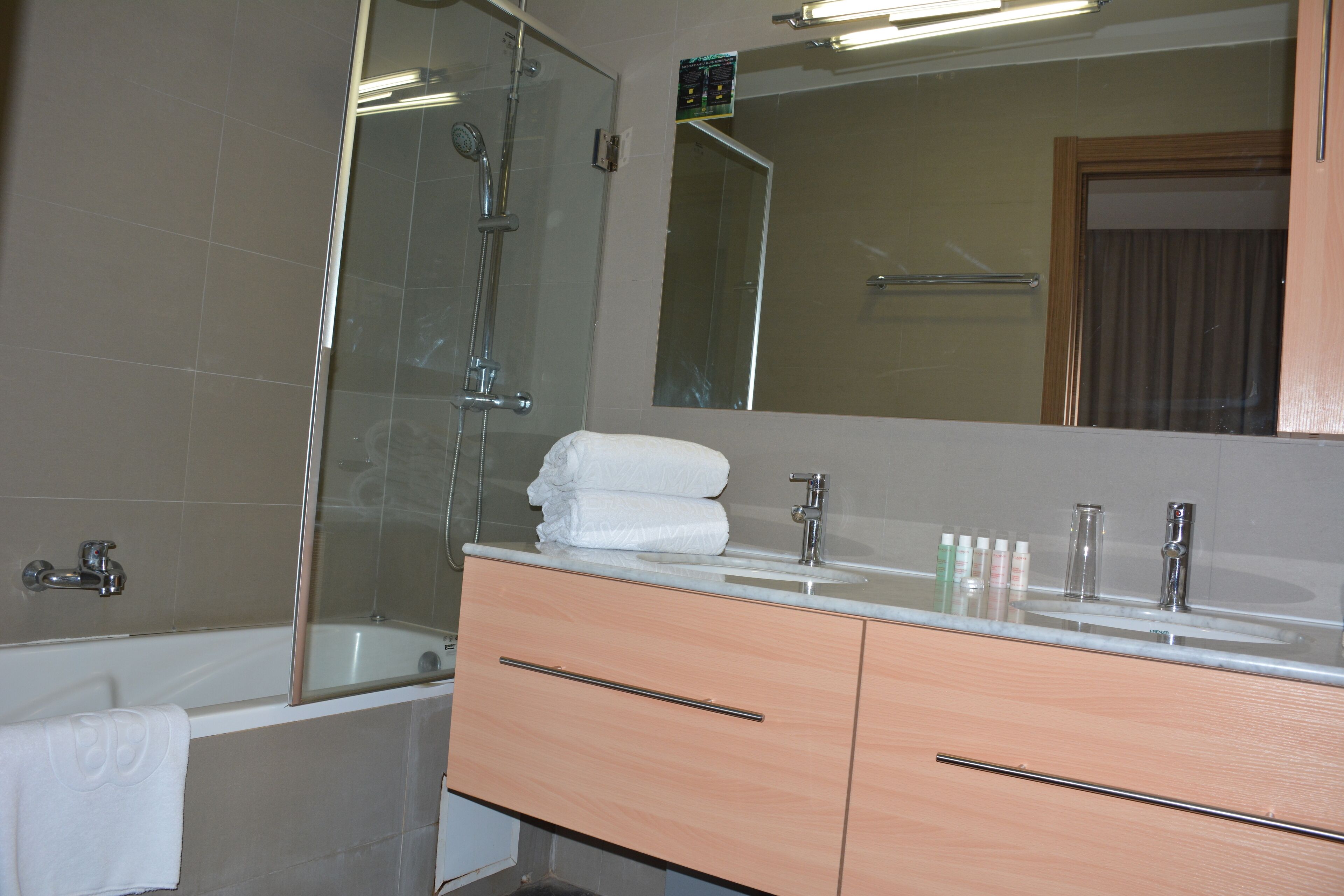 A modern bathroom with a bathtub, a glass shower enclosure, a vanity with a sink, and a large mirror.