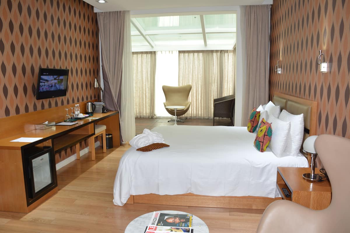 A hotel room with a bed, a desk, a chair, a TV, and a magazine on the floor.
