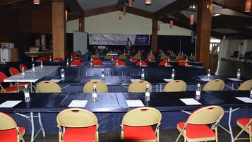 A conference room with multiple tables and chairs, arranged in rows.