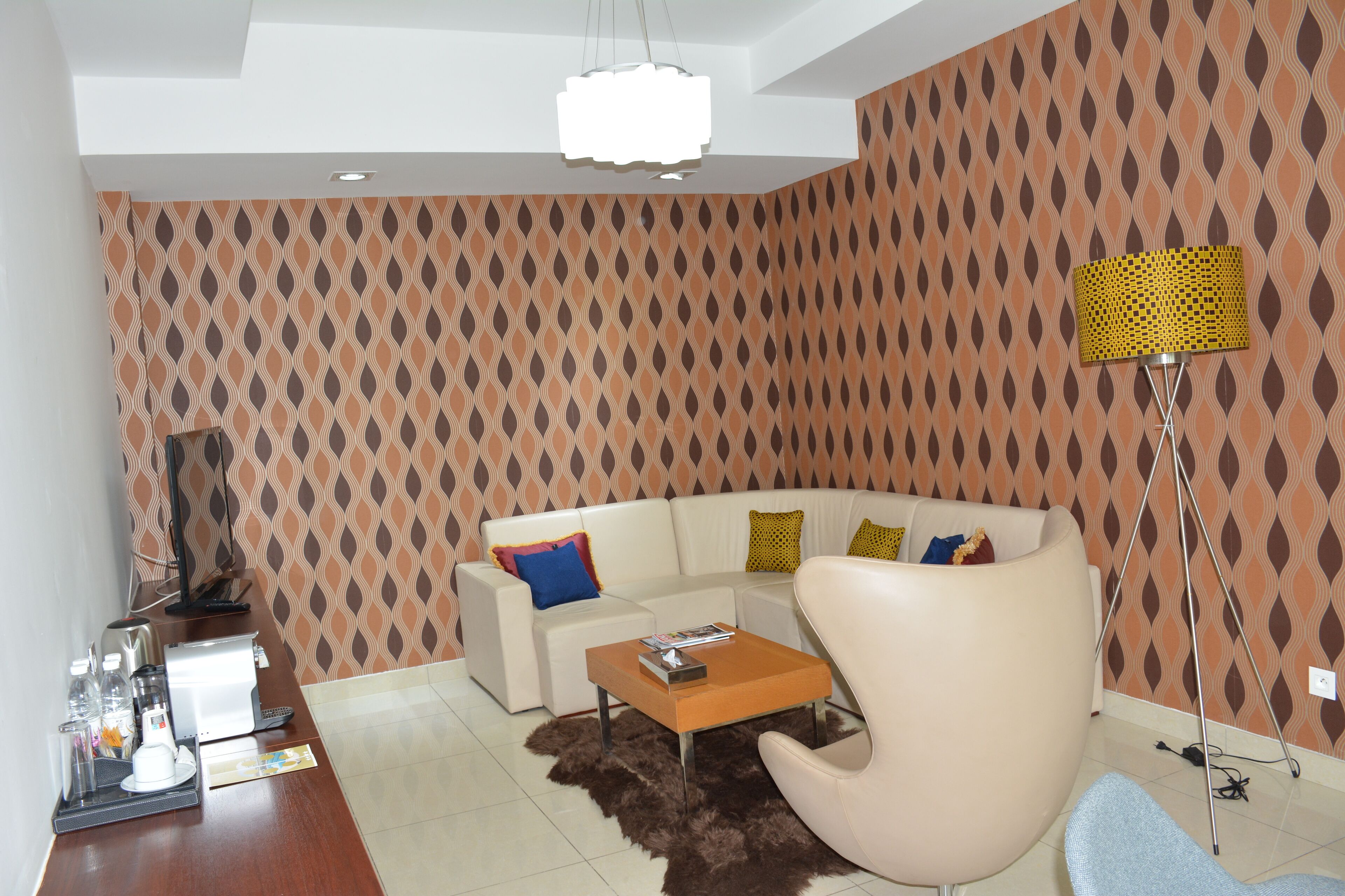 Een moderne woonkamer met een witte bank, een houten bijzettafeltje en een behang met patroon.