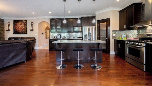 A modern kitchen with dark cabinets, stainless steel appliances, and a central island with bar stools.