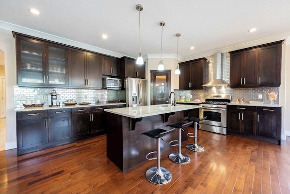 A modern kitchen with dark wood cabinets, stainless steel appliances, and a central island with bar stools.