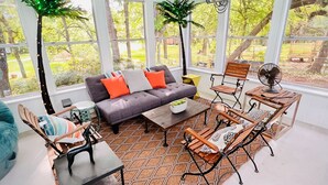 Une véranda aménagée avec un canapé, une table basse, des fauteuils et de grandes fenêtres.