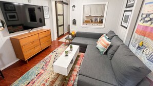 Un salon moderne avec un canapé gris, un meuble en bois et un grand téléviseur à écran plat.