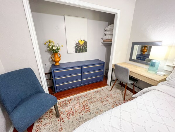 A bedroom with a bed, a desk, a chair, a dresser, and a rug.