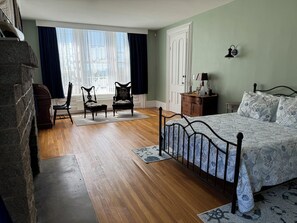 A bedroom with a bed, two chairs, a dresser, and a window with curtains. - Captain Sweetser's Inn (Searsport)