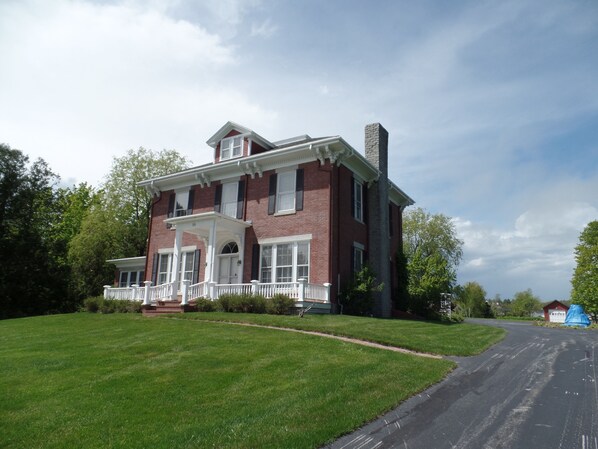 A two-story brick house with a front porch and a chimney. - Captain Sweetser's Inn (Searsport)