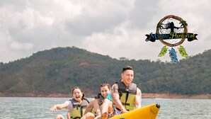 Eine Gruppe von Menschen auf einem gelben und blauen Floß auf dem Wasser, mit Hügeln im Hintergrund.