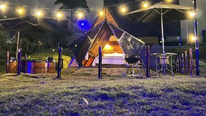 Ein Campingplatz mit Zelten, Lichterketten, einem Grill und einem Tisch unter einem Baldachin.