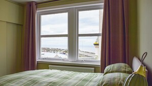 A bedroom with a large window, a bed, and a bedside lamp. - 3 bedroom accommodation in Anstruther (Anstruther)