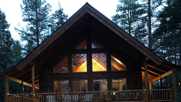 A log cabin with a balcony, large windows, and outdoor seating. - Beautiful & Brand New Cabin in Duck Creek  (Duck Creek Village)