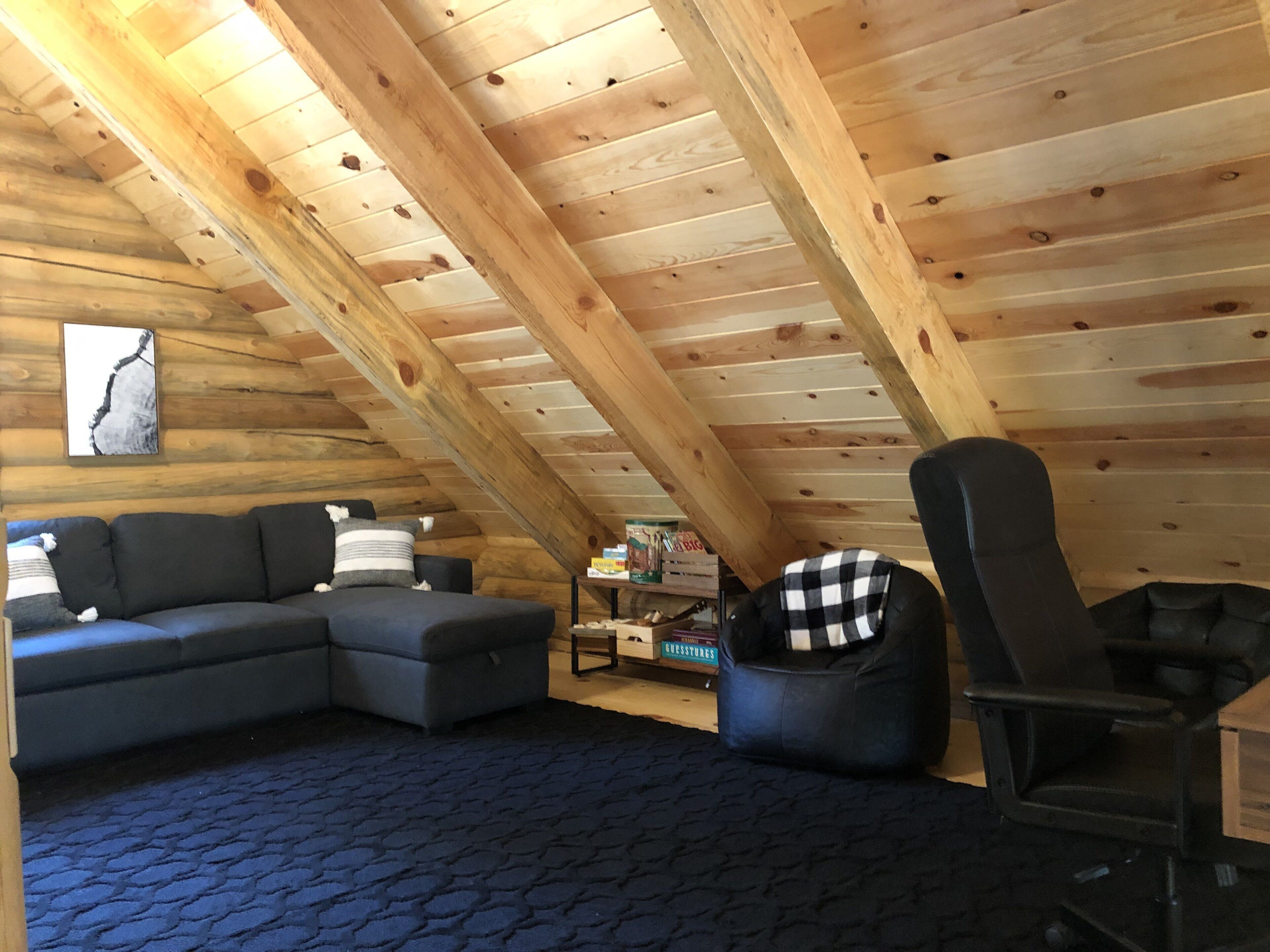 Et interieur af en hytte med en sofa, en stol og et lille bord.